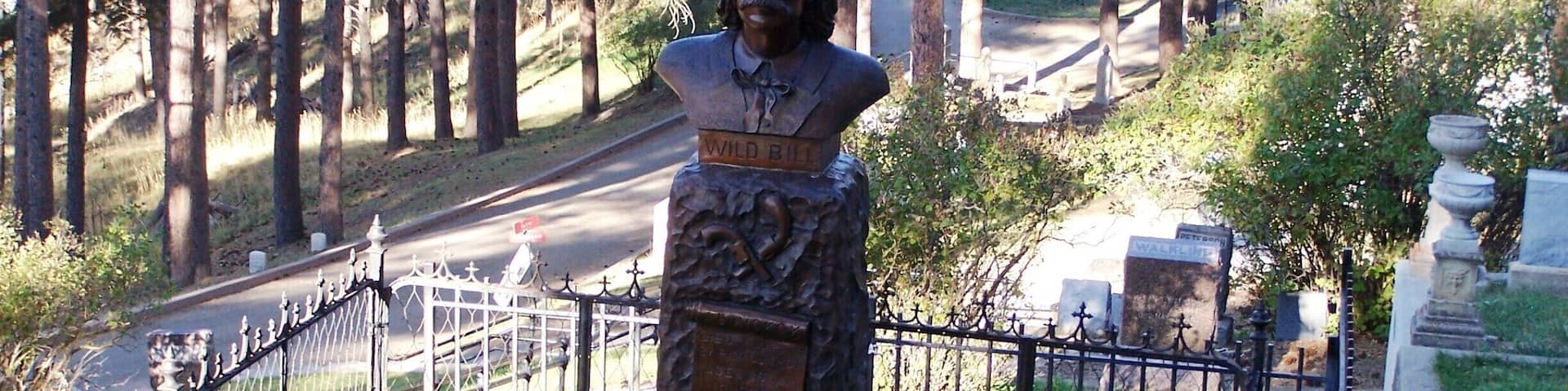 The most important event in Deadwood, South Dakota history was a poker game in Saloon #10 on August 2, 1876, where the sniveling coward Jack McCall snuck up and shot Wild Bill Hickok in the back of the head. Hickok had arrived in Deadwood only a few weeks earlier, played a succession of card games, and never in his life sat with his back to the door. Until that day.
Above the town, on a ridge, tourists can visit the graves of Wild Bill and Calamity Jane in Mount Moriah Cemetery.