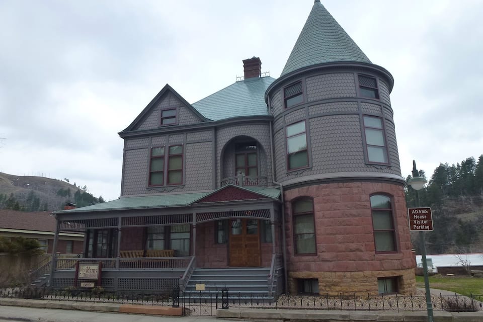 A historic house with a turret and a porch.