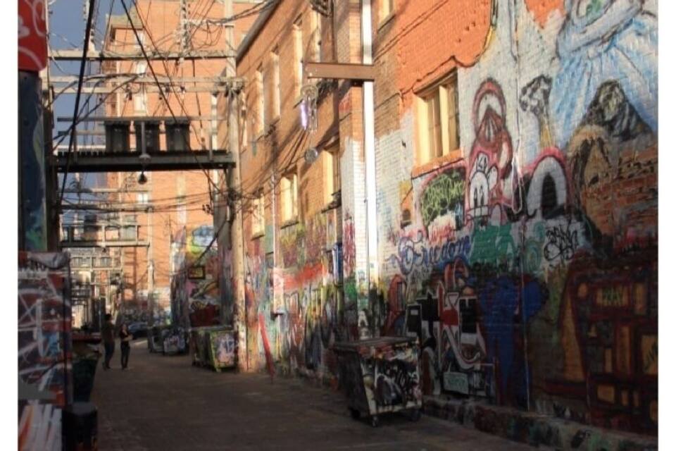 An alley with graffiti-covered walls and overhead power lines.