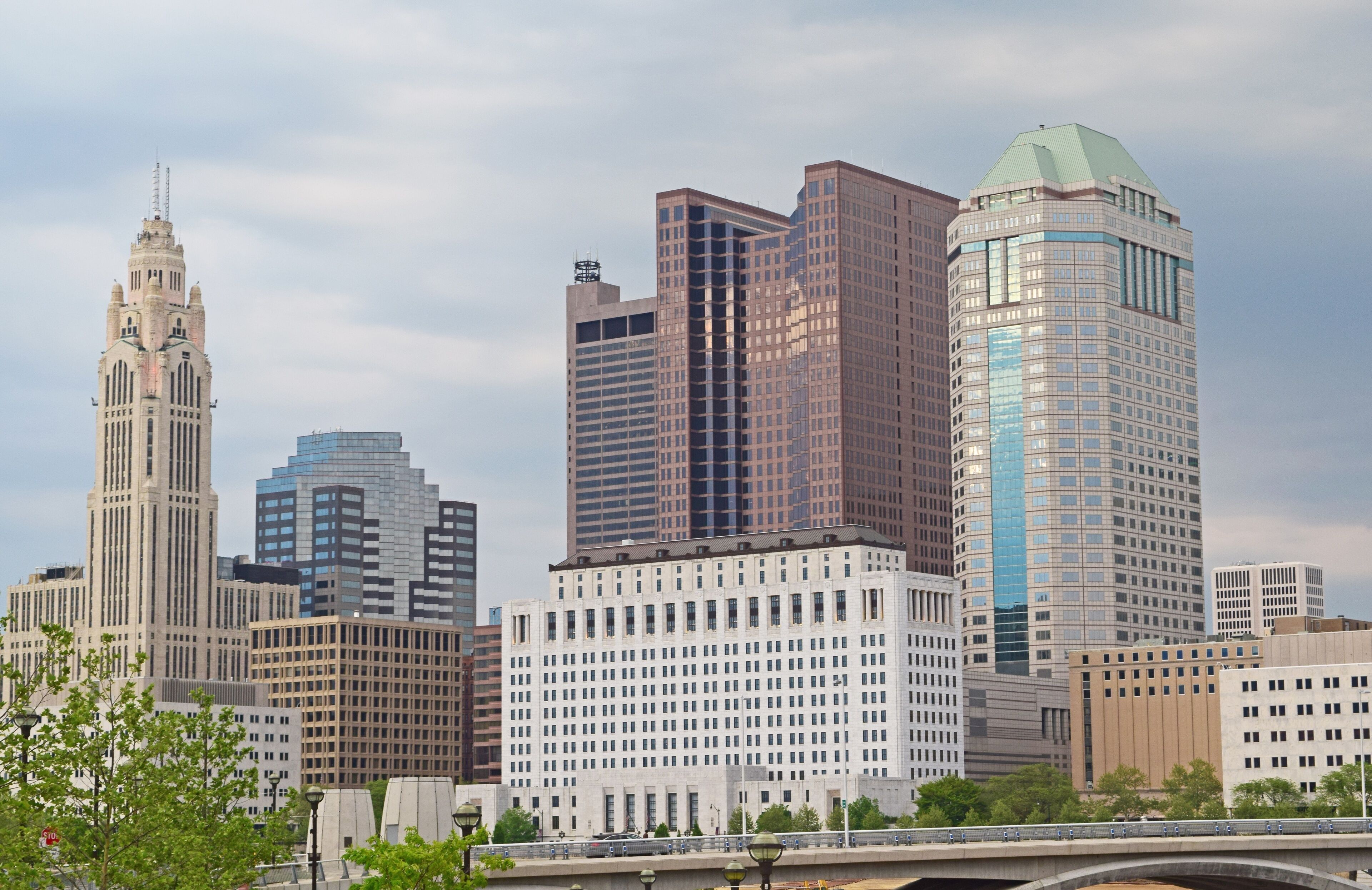 A city skyline with a mix of modern and historic buildings, including a prominent tower and a bridge in the foreground.