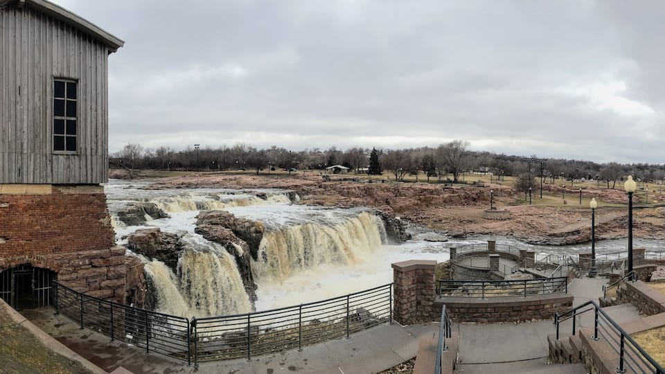 A waterfall, a brick building, and a park with pathways and lampposts.