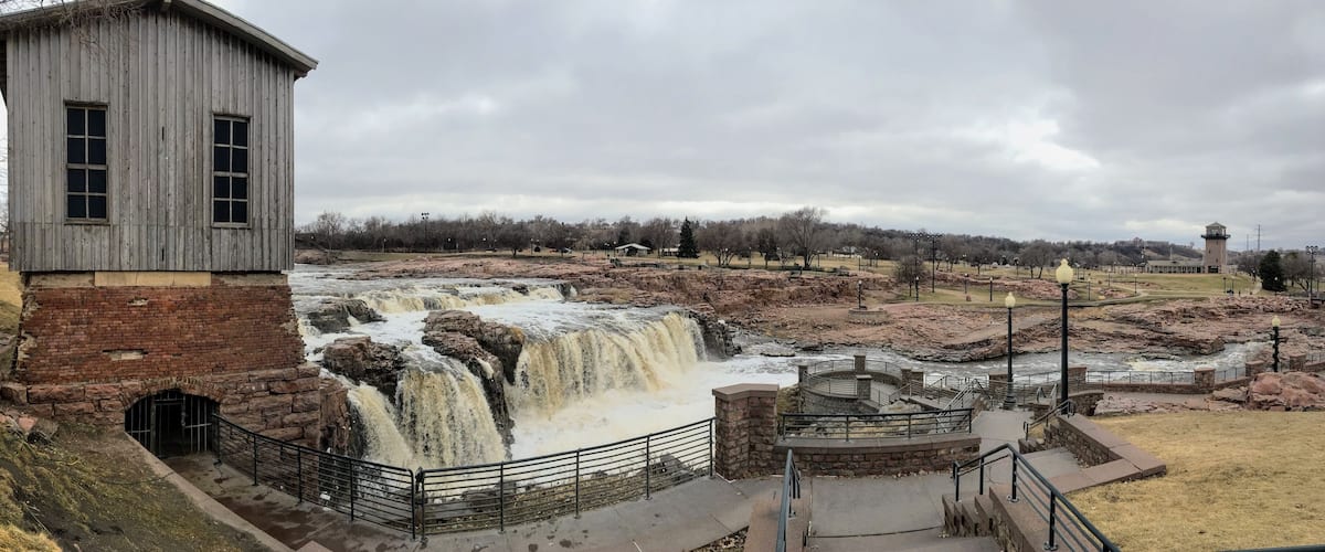 A waterfall, a brick building, and a park with pathways and lampposts.