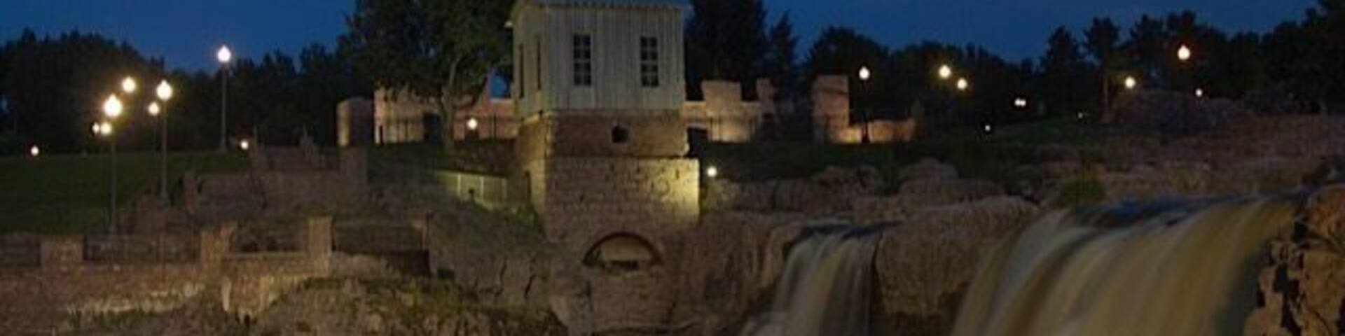 A historic stone building with a waterfall in the foreground.