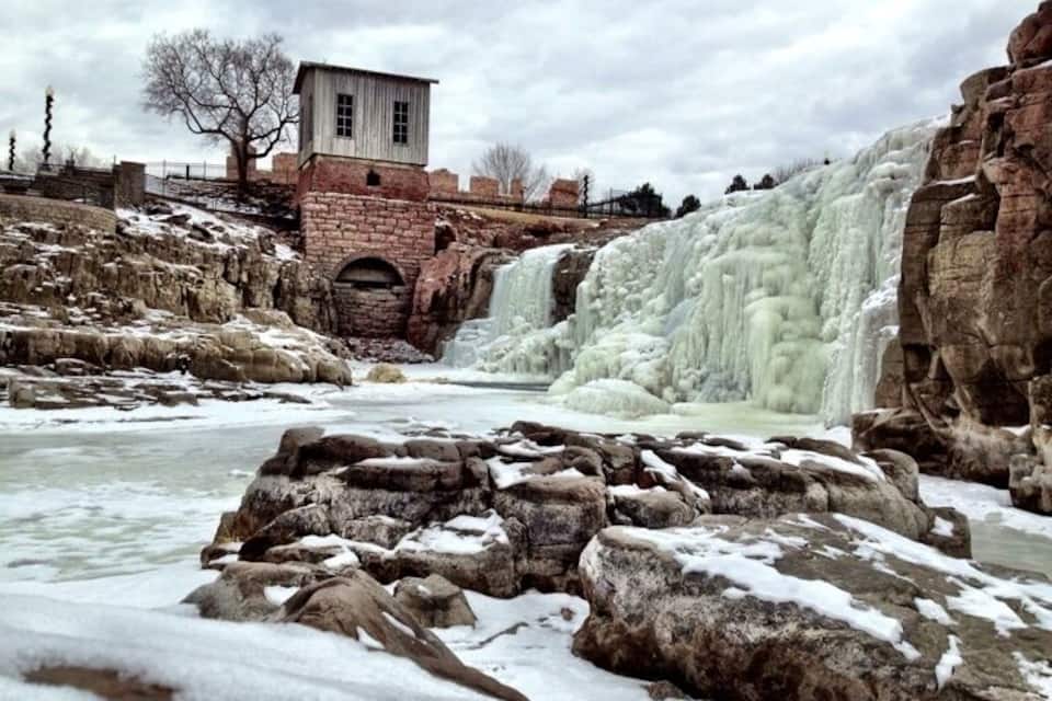 Una cascada gelada amb una construcció de maó al fons.