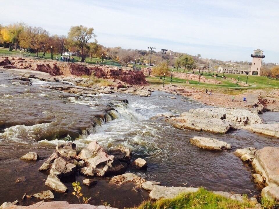 Une rivière aux rives rocheuses, avec un phare en arrière-plan.
