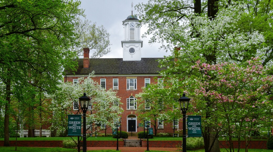 A brick building with a clock tower, surrounded by blooming trees and a brick pathway.