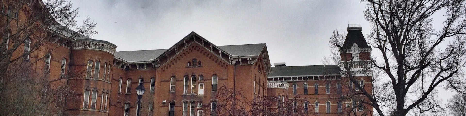 Called "The Ridges" currently, this large, looming building that overlooks Ohio University's campus was formerly a mental health hospital called the Athens Asylum for the Insane. There's a small museum inside now, and the rest of the grounds are owned by the university, but there is still certainly a chilling aspect to the building that calls to its past.
Take a walk around the grounds or visit the museum, it's something worth seeing. Behind the building is a community park with areas that would be worth visiting in warmer days. Take the road that loops up a hill (to the left of a campus sign) and you can view the cemetery of unnamed, forgotten patients who died and were only assigned a number. There are efforts to find the names of these individuals and give them the attention that is deserved. There's also a beautiful nature walk that I would have taken if it wasn't so cold!
#roadtrips #ohio #historic #hospitals #roadtrip