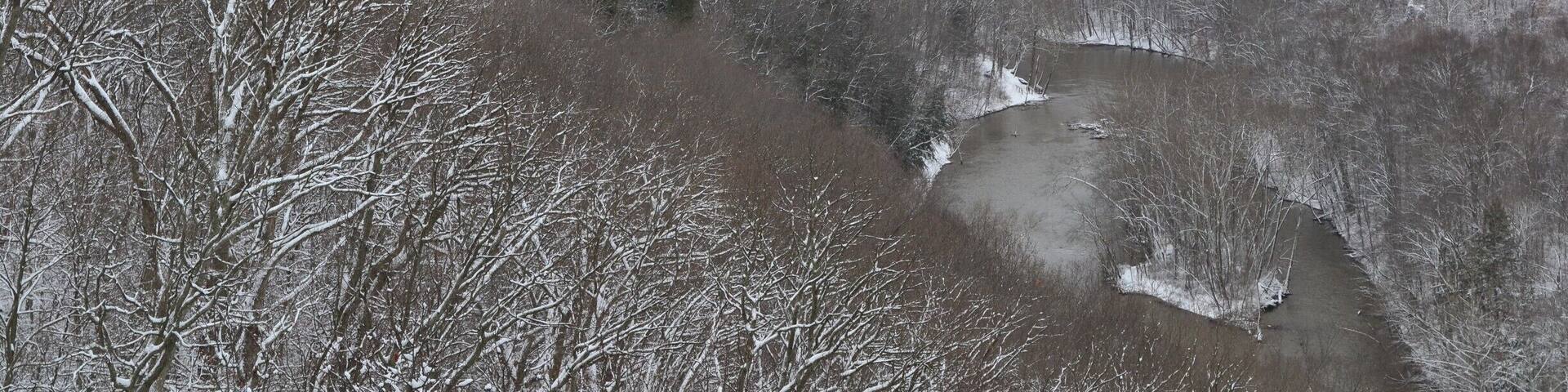 A snow-covered landscape with a river winding through a forested valley.