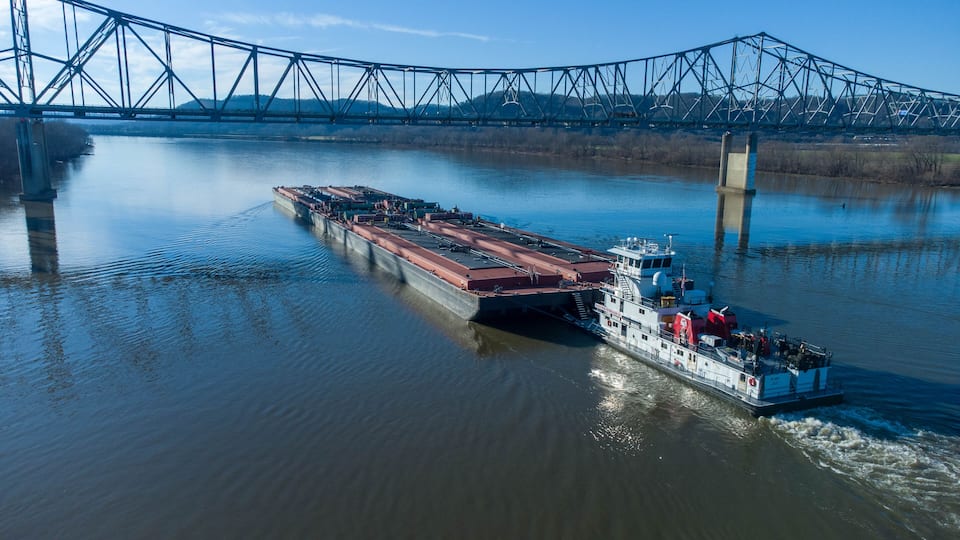 A cargo ship on a river with a bridge in the background.