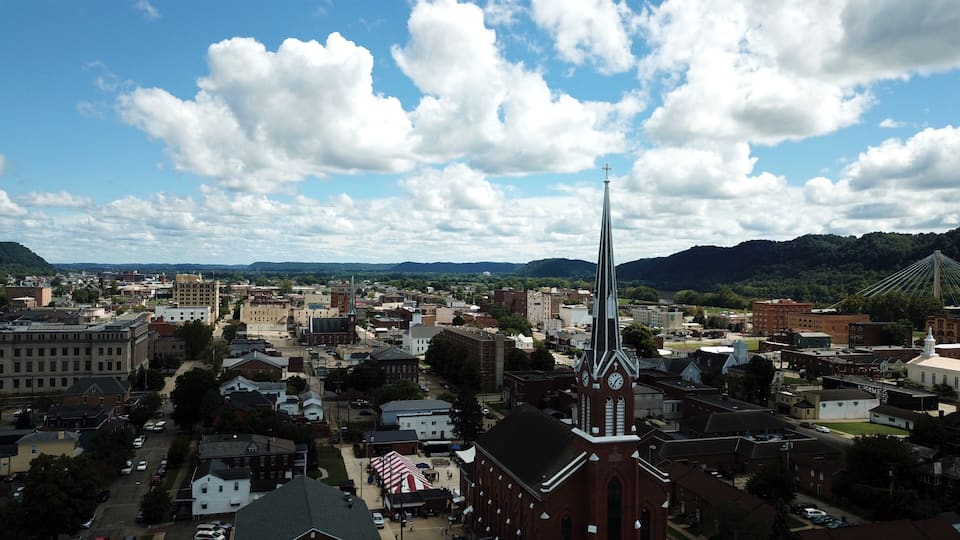 A town with a prominent church steeple, a large clock tower, and a bridge in the distance.
