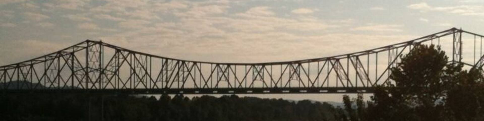 A bridge over a body of water with trees in the foreground.