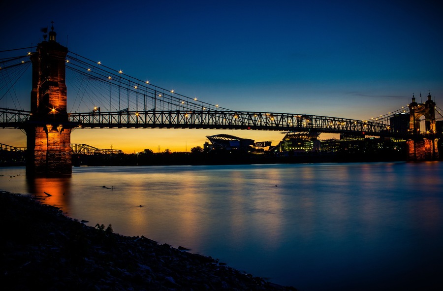 A bridge at dusk with lights reflecting on the water.