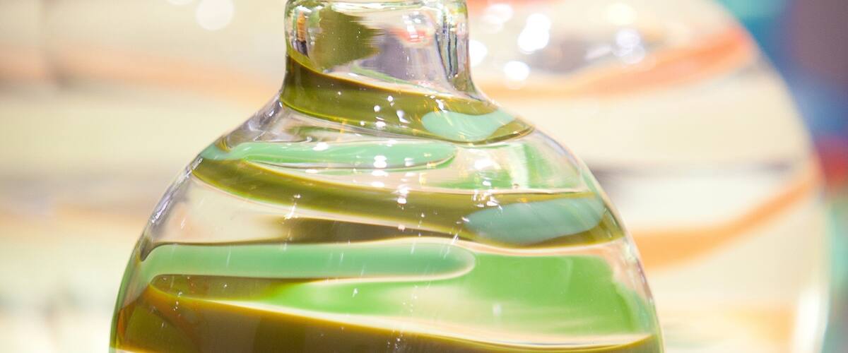 A clear glass bottle with green liquid.