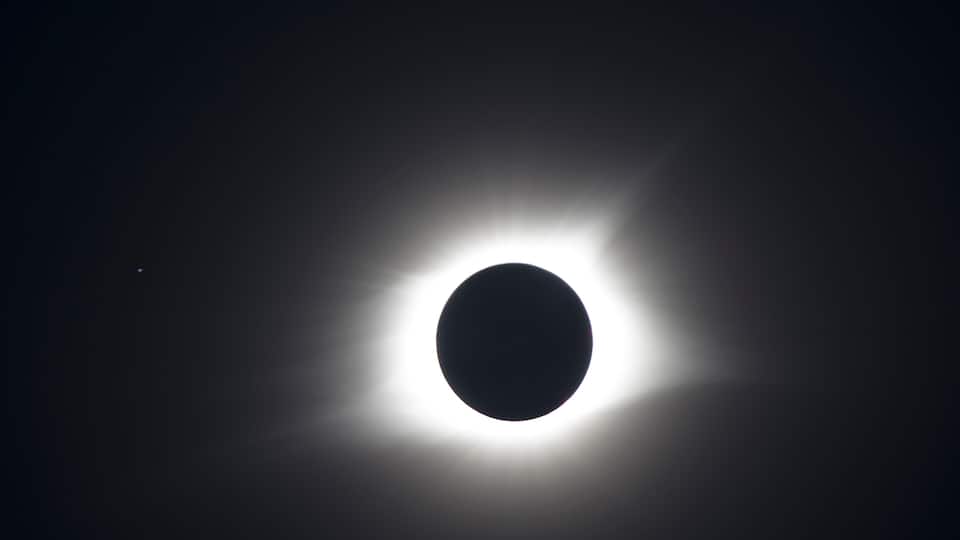 A solar eclipse with a dark moon center and bright corona.
