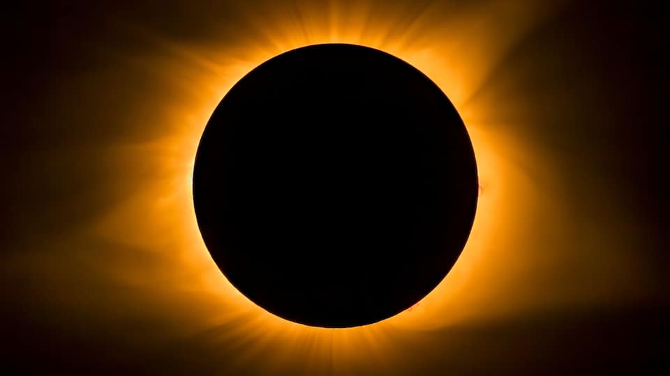A solar eclipse with a dark central area surrounded by a bright corona.