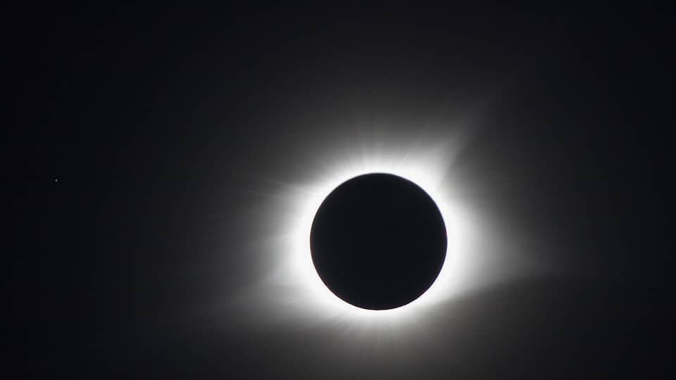 A solar eclipse with a dark moon center and bright corona edges.
