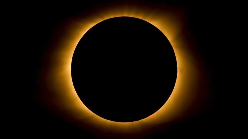 A solar eclipse with a darkened sun at the center and a glowing corona.