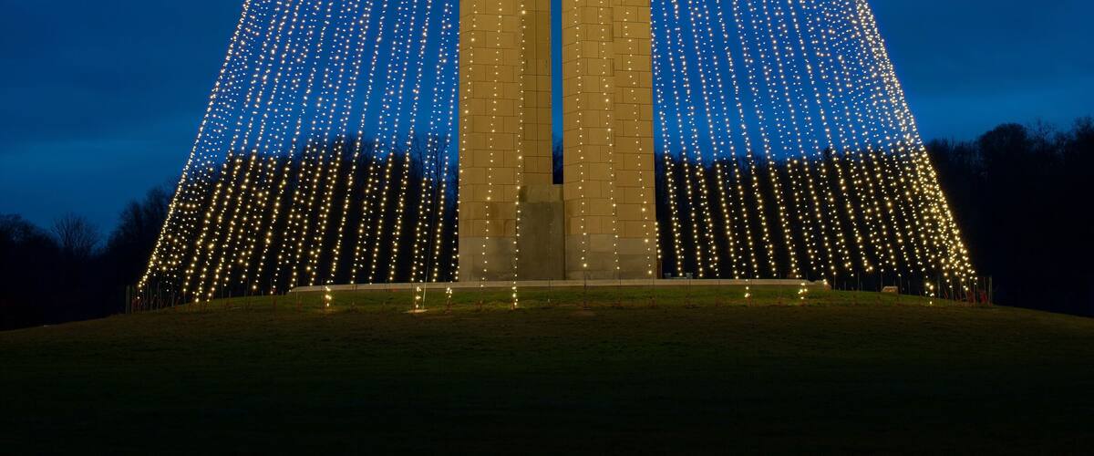 A pyramid-shaped structure with a central opening, surrounded by a field of lights.