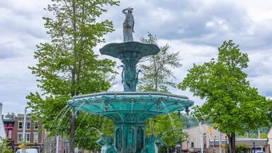 The Broadway Fountain in Madison, Indiana with spring trees, and clouds.