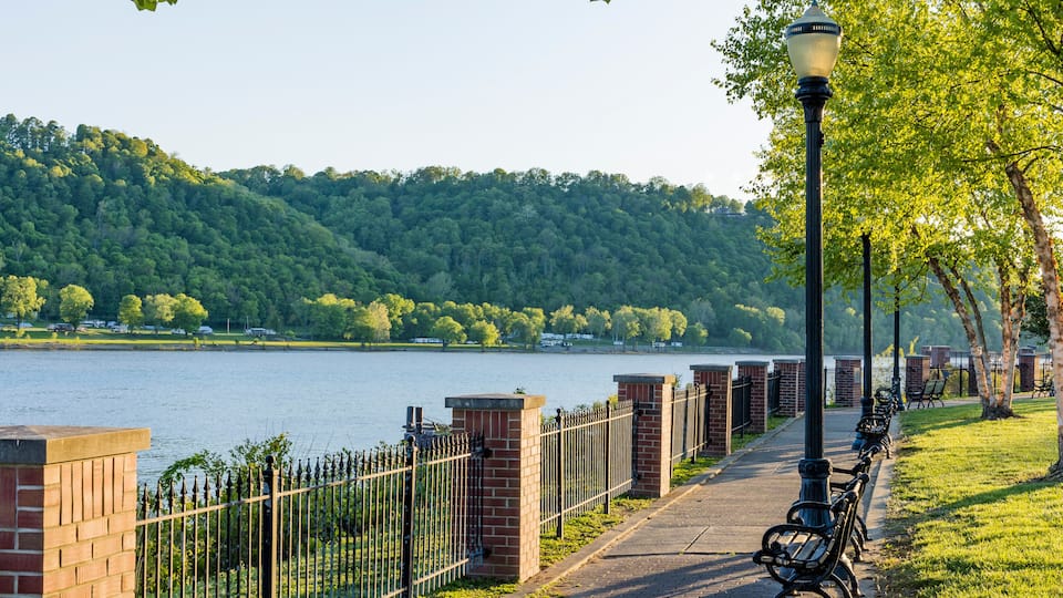 Walkway along the Ohio River in Madison, Indiana with a wrought iron fence and lamp posts in the evening.