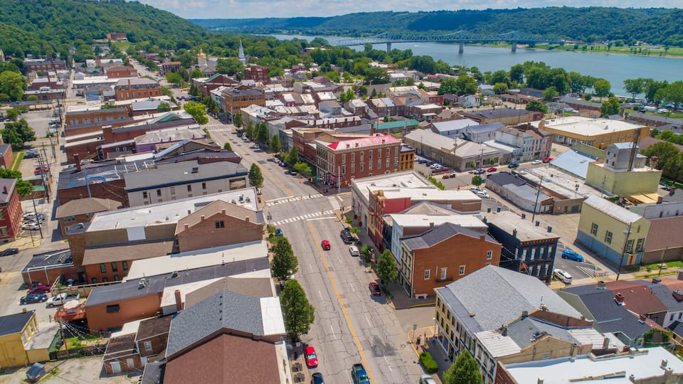 A town with a river, a bridge, and a mix of historic and modern buildings.