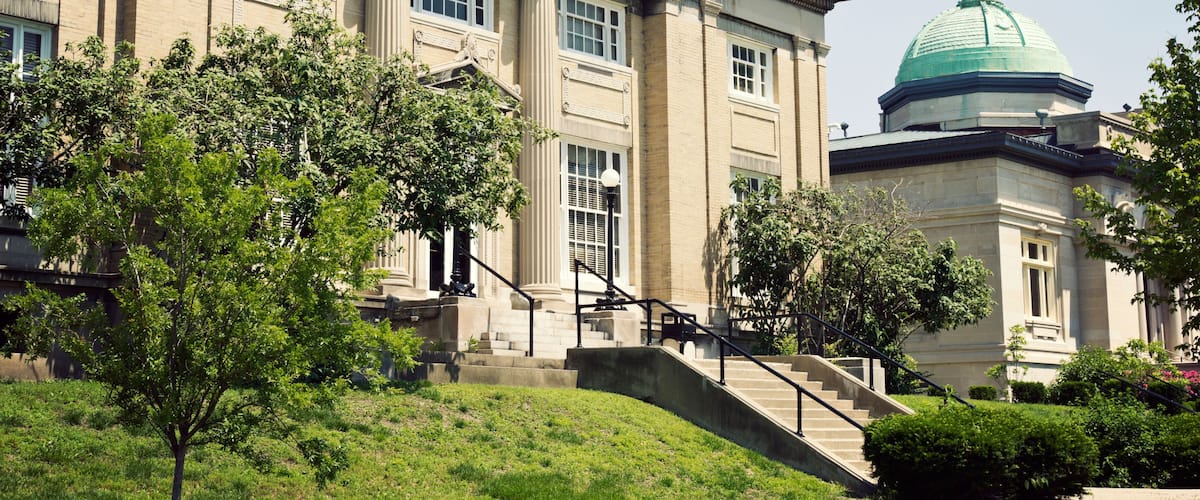 A large building with a dome and columns, surrounded by trees and a grassy area.