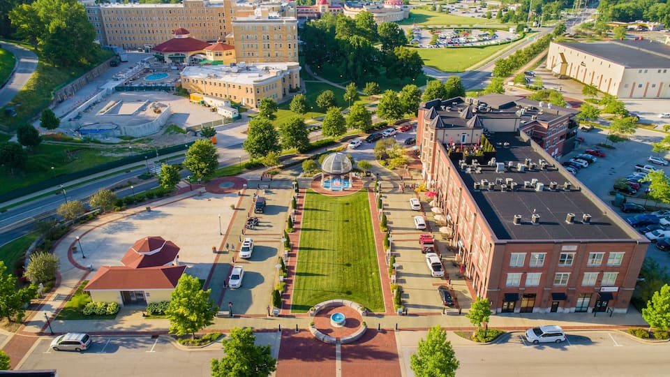 An aerial view of a university campus with multiple buildings, a central lawn, and surrounding roads.