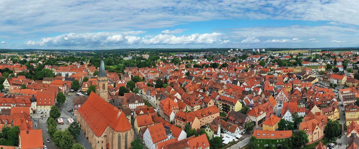 A panoramic view of a town with red-roofed buildings, a prominent church, and a clear sky.