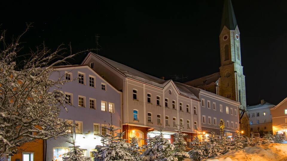 A snow-covered street with historic buildings and a church tower.