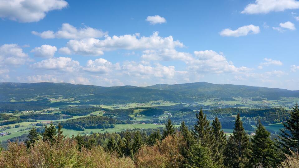 A panoramic view of a mountainous landscape with scattered houses and dense forests.