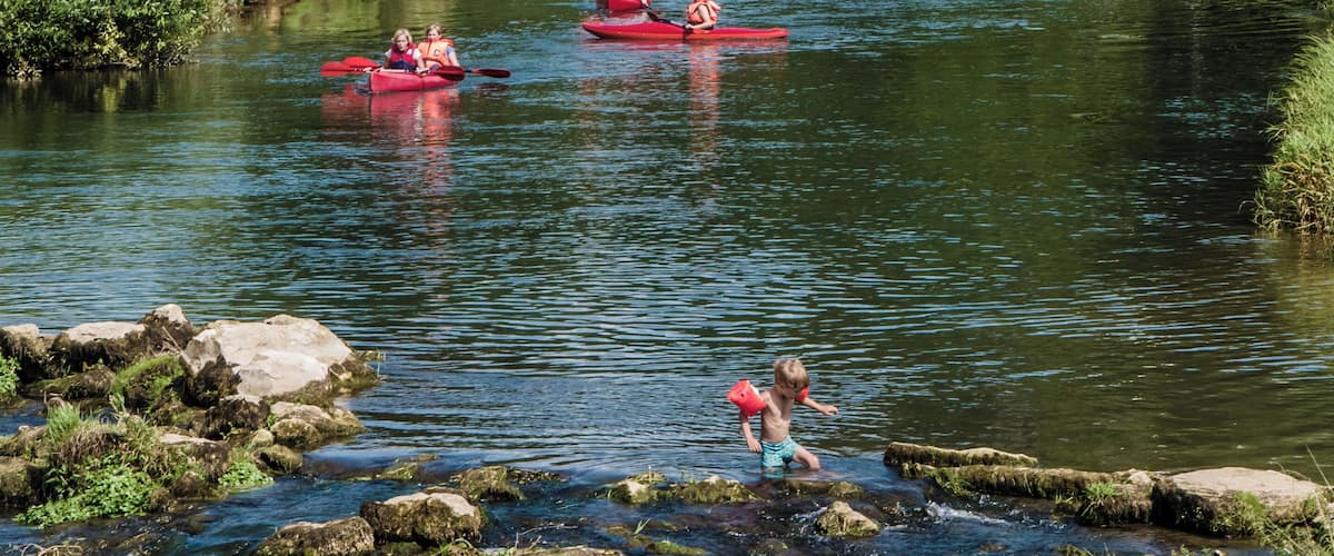 Swimmers and boaters in the Wiesent beneath the ruin Neideck in Streitberg
