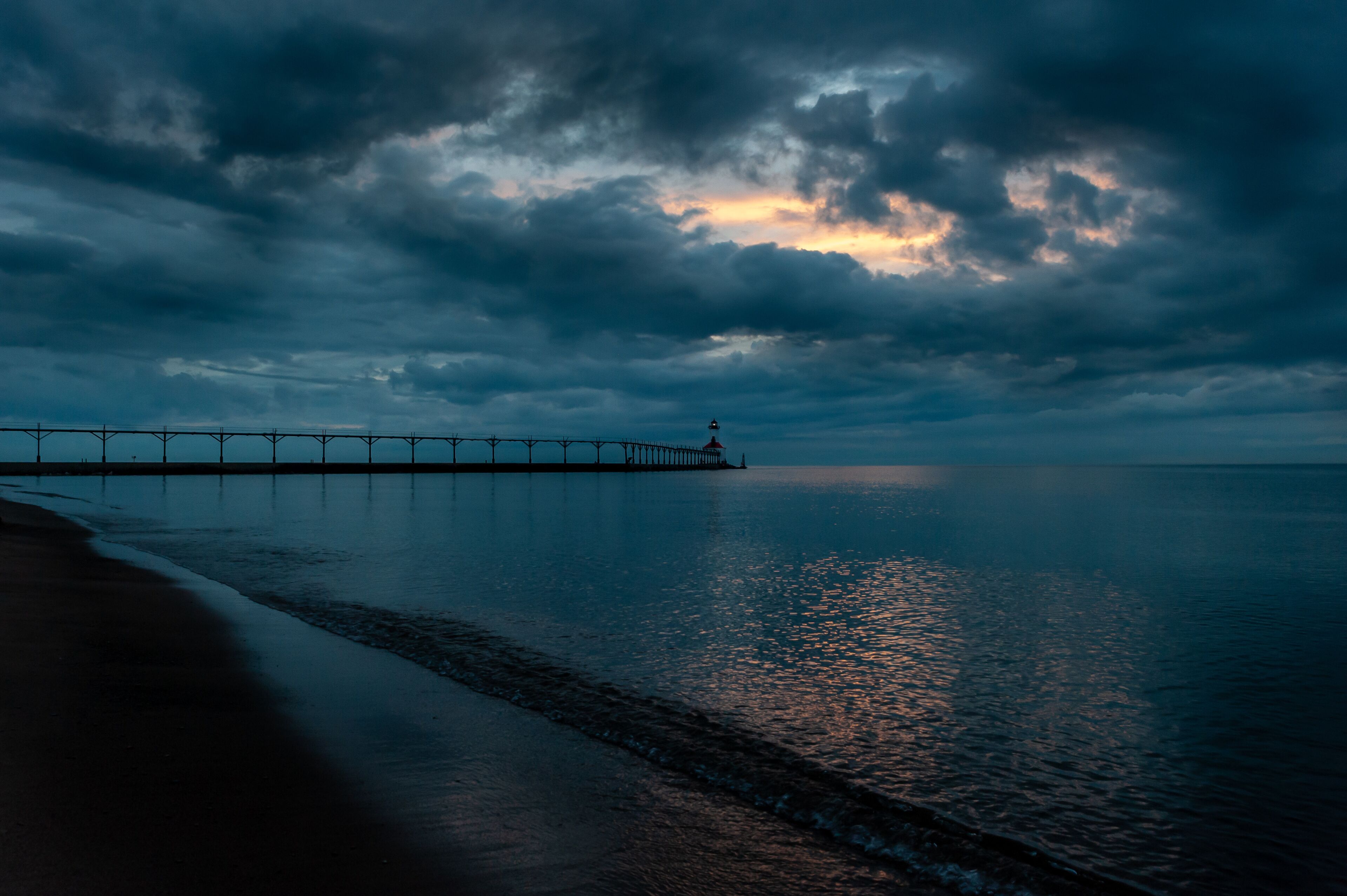 Stormclouds part over lighthouse along beach in michigan city indiana