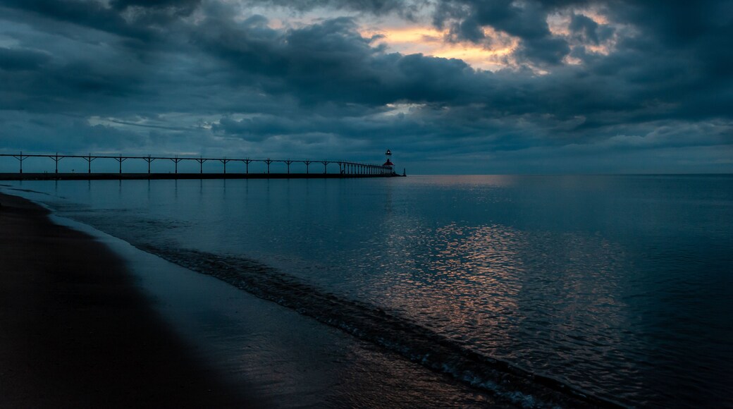 Stormclouds part over lighthouse along beach in michigan city indiana