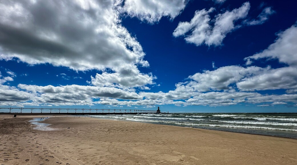Panoramic landscape view of the beach and the Michigan City Lighthouse in summer with dramatic cloudscape