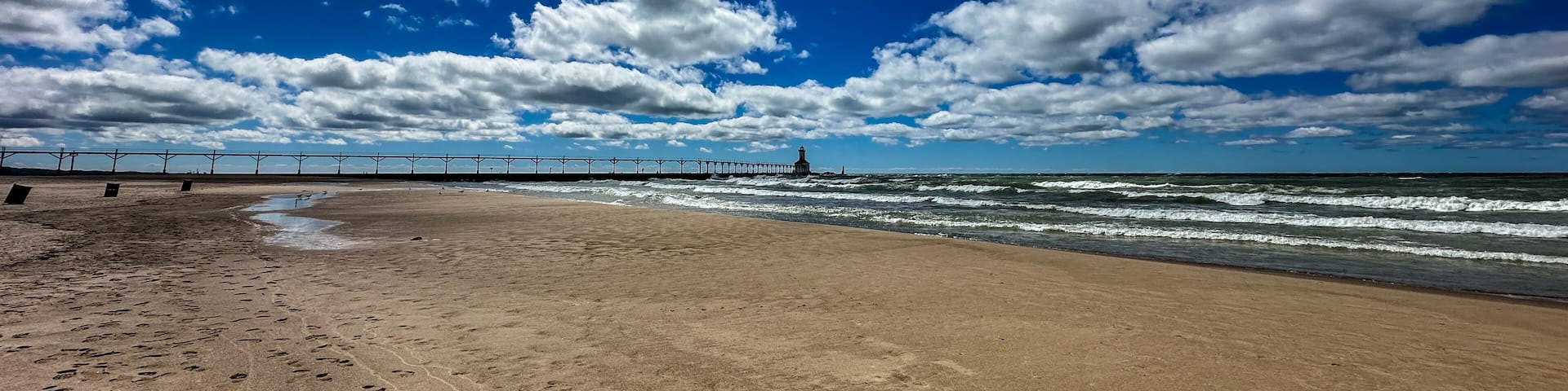Panoramic landscape view of the beach and the Michigan City Lighthouse in summer with dramatic cloudscape