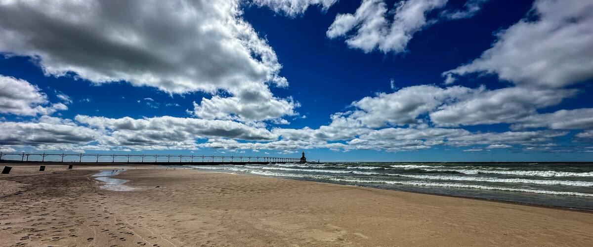 Panoramic landscape view of the beach and the Michigan City Lighthouse in summer with dramatic cloudscape