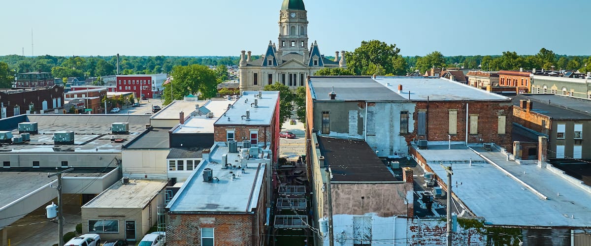 A town with a prominent clock tower, a mix of historic and modern buildings, and a clear blue sky.