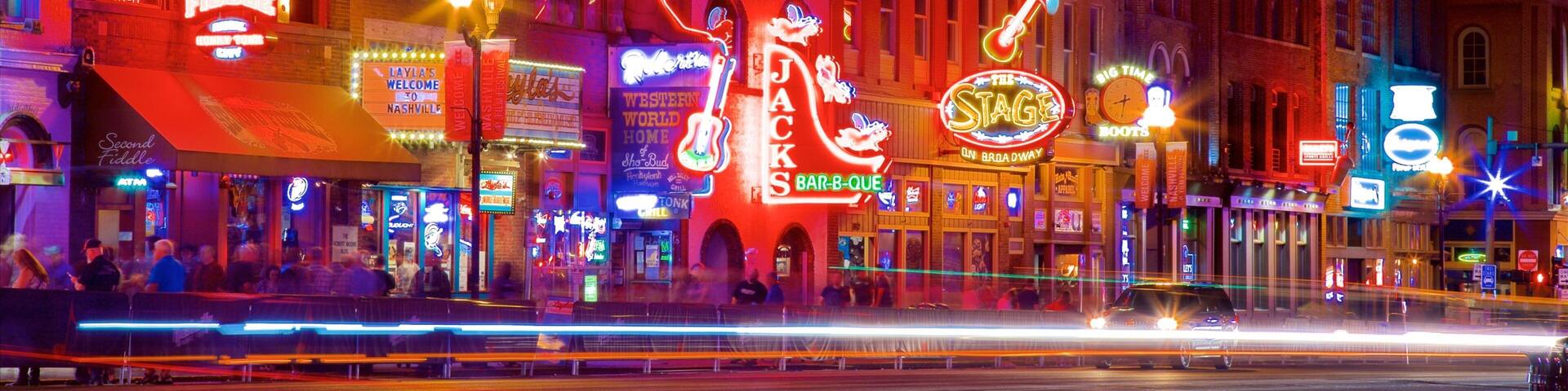 A brightly lit street with neon signs and a large illuminated figure of a woman.