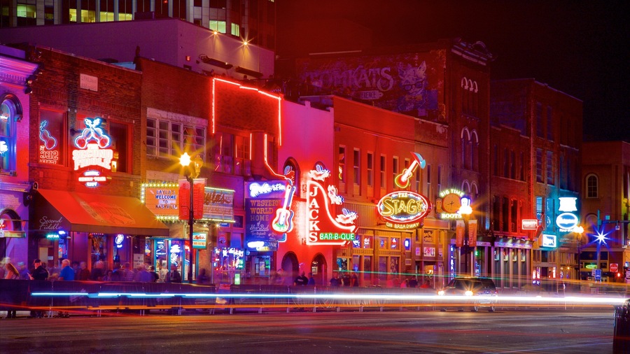 A brightly lit street with neon signs and a large illuminated figure of a woman.