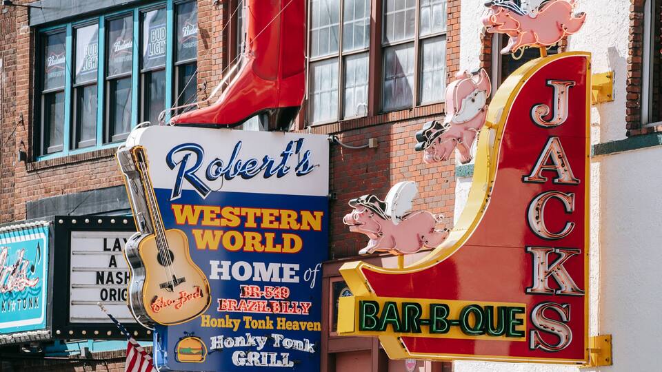 Segno a tema western con luci al neon e una chitarra, pubblicità di Robert's Western World.