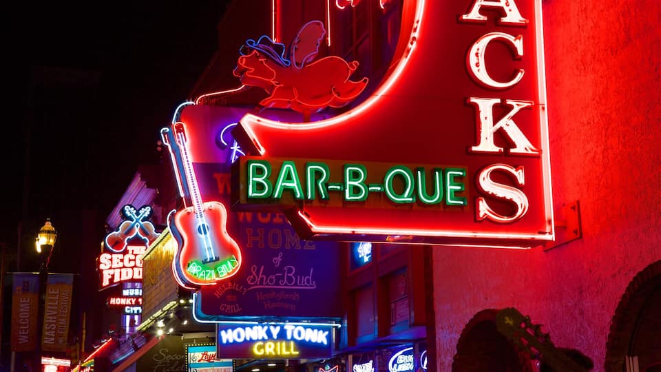 Neon signs for 'Bar-B-Que' and 'Monkey Tonk Grill' in a vibrant, illuminated setting.