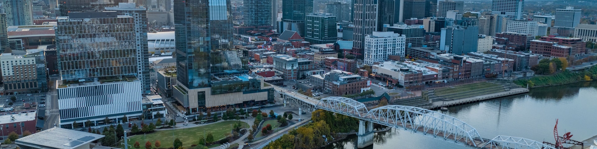Paisagem urbana com arranha-céus modernos, um rio e uma ponte.