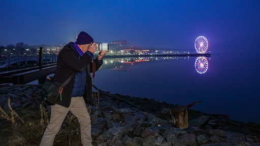 Washington DC USA A photographer photographs the Capital Wheel in the Washington National Harbor at night.