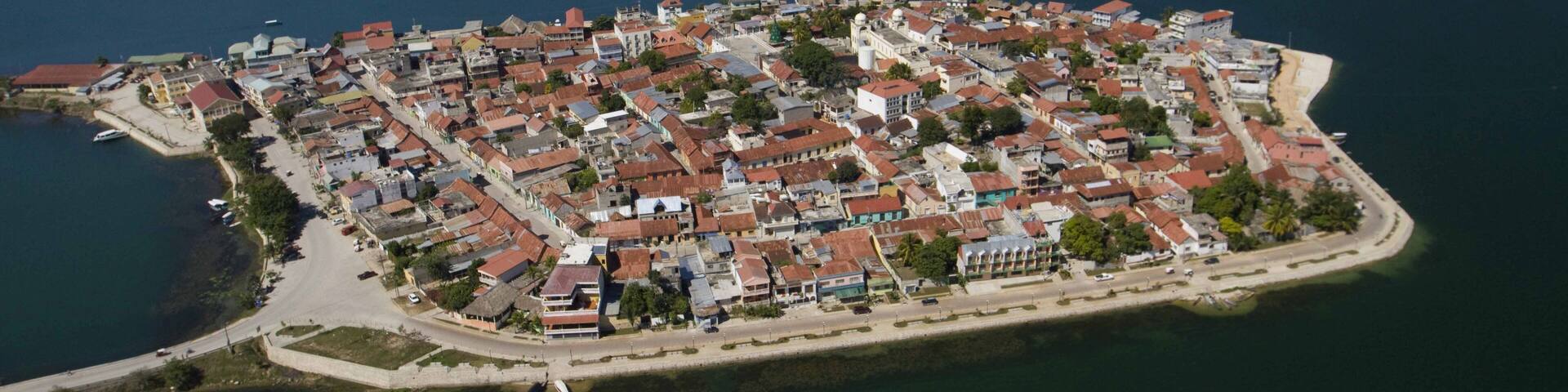 An aerial view of a coastal town with a dense cluster of buildings, a prominent church, and surrounding water bodies.