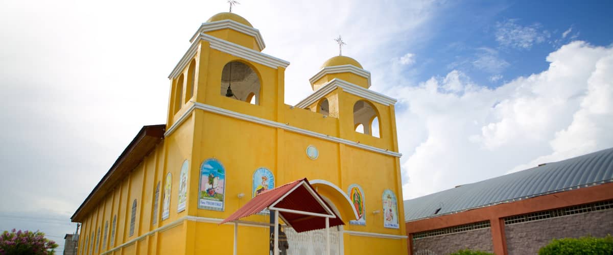 A yellow church with two bell towers and a red roof.