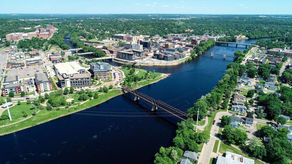 An aerial view of a city with a river, bridges, and surrounding greenery.