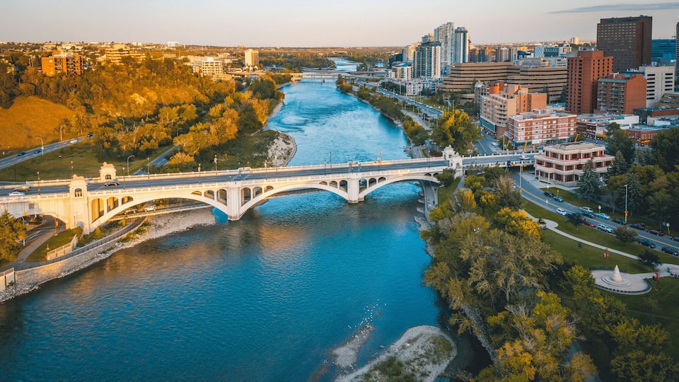 A river with a bridge, urban buildings, and a park area.
