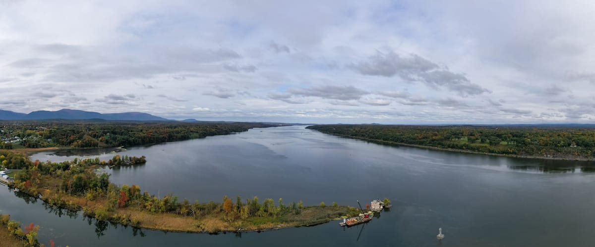 A river meandering through a forested landscape with a small island and a dock.