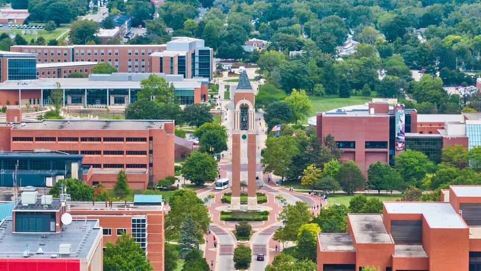 A campus with a central tower, surrounding buildings, and green spaces.