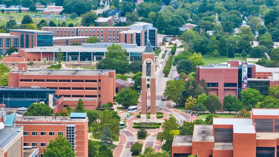 A campus with modern buildings, a central tower, and surrounding greenery.